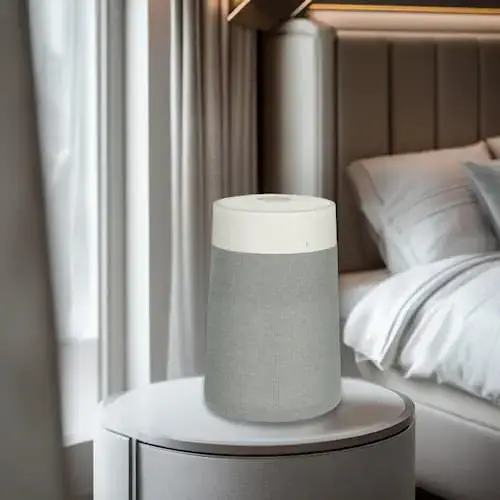 Purificateur Blueair 511iMax posé sur une table de chevet dans une chambre lumineuse avec rideaux blancs