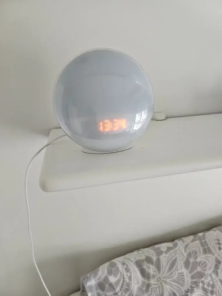 Photo réelle du réveil simulateur d’aube Artinabs installé sur l’étagère au-dessus du lit, test 6 mois — distance ≈40 cm