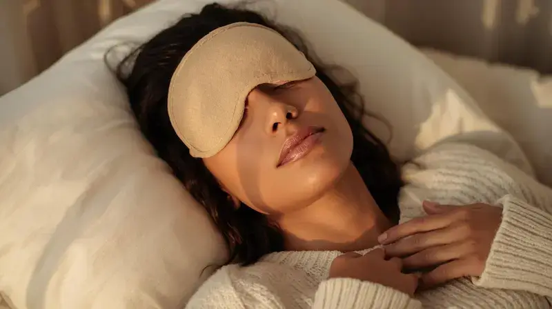Femme se relaxant avec un masque yeux thermique beige allongée sur un lit