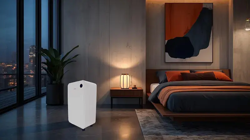 Déshumidificateur Air and Me Lary blanc posé au sol dans une chambre moderne avec vue urbaine, mobilier en noyer et décoration terracotta