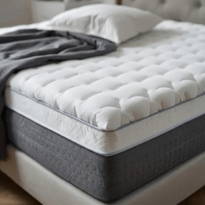 Surmatelas Mello Duo : avis sur ce modèle double couche Surmatelas Mello Duo avec housse matelassée en percale de coton sur un lit, vu en angle avec oreillers et linge de lit.