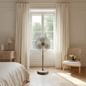 Rafraîchir une pièce avec un ventilateur : les méthodes qui fonctionnent vraiment Ventilateur sur pied placé devant une fenêtre ouverte dans une chambre lumineuse pour améliorer la fraîcheur ressentie en été.