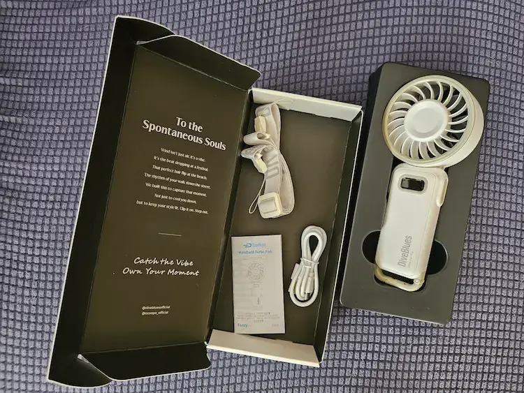 Contenu de la boîte du ventilateur portable Diveblues avec le ventilateur, la dragonne, le câble USB-C et la notice.